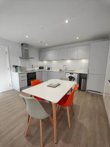 a kitchen with a white table and chairs at 8 Putsborough - Luxury Apartment at Byron Woolacombe, only 4 minute walk to Woolacombe Beach! in Woolacombe