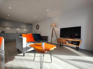 a living room with a couch and a table and a television at 8 Putsborough - Luxury Apartment at Byron Woolacombe, only 4 minute walk to Woolacombe Beach! in Woolacombe