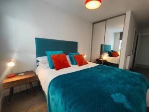 a bedroom with a large bed with blue and orange pillows at 8 Putsborough - Luxury Apartment at Byron Woolacombe, only 4 minute walk to Woolacombe Beach! in Woolacombe