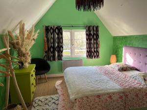 Dormitorio verde con cama y ventana en Gîte Le Chat Chez Qui J'habite, en Saint-Aubin-sur-Mer