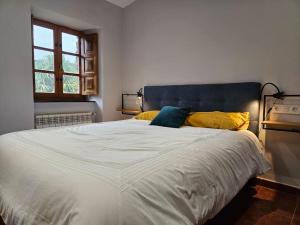 1 dormitorio con 1 cama blanca grande con almohadas amarillas y azules en 10A04 Casa Petacos, en Pravia