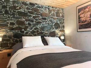 Un dormitorio con una pared de piedra y una cama en Le 30, en Troistorrents
