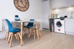 a kitchen with a table and chairs and a washing machine at 7 Putsborough - Luxury Apartment at Byron Woolacombe, only 4 minute walk to Woolacombe Beach! in Woolacombe