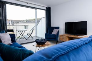 a living room with a blue couch and a large window at 7 Putsborough - Luxury Apartment at Byron Woolacombe, only 4 minute walk to Woolacombe Beach! in Woolacombe