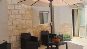 a patio with two chairs and a table with an umbrella at Aida Guest house in Nazareth