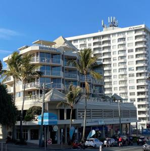 a large white building with palm trees in front of it at License To Chill • Couple’s Escape in Mooloolaba in Mooloolaba