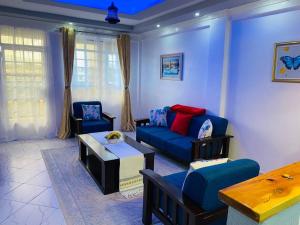 a living room with a blue couch and chairs at Levi's 1 Bedroom Apartment California Plaza Nanyuki in Nanyuki