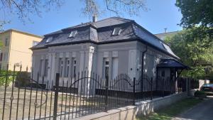 a white house with a black roof behind a fence at Karpatia Vendeghaz 1201 Budapest in Budapest