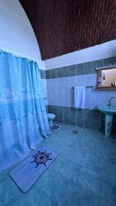 a bathroom with a blue shower curtain and a sink at Pharaonicas in Al Aqālitah