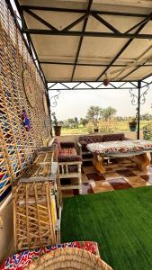 a patio with benches and a green lawn at Pharaonicas in Al Aqālitah