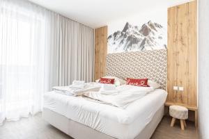 Schlafzimmer mit einem Bett mit weißer Bettwäsche und roten Kissen in der Unterkunft Alpenrock Schladming by ALPS RESORTS in Schladming