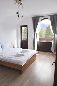 - une chambre avec un grand lit et une grande fenêtre dans l'établissement Cosy&Minimalistic Apartments - Haret Building, à Sinaia