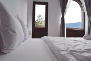 a bedroom with a white bed with a window at Cosy&Minimalistic Apartments - Haret Building in Sinaia