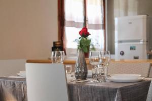 une table avec une rose rouge dans un vase avec des verres dans l'établissement Garda residence Gardaland, à Castelnuovo di Verona