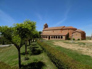 un viejo edificio de ladrillo con un árbol delante de él en CASAS RURALES LAS ERAS 1 Y 2, en Santa María de Riaza