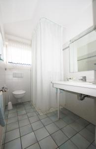 ein weißes Bad mit einem Waschbecken und einem WC in der Unterkunft Land-gut-Hotel Rohdenburg in Lilienthal