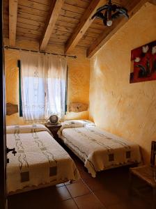 two beds in a room with a window at Casas Rurales Las Eras I A Y II B in Santa María de Riaza