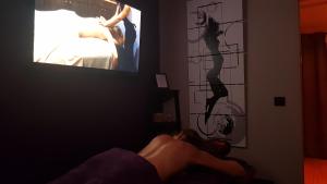 a woman laying on a bed in front of a tv at SECRET33 in Floirac