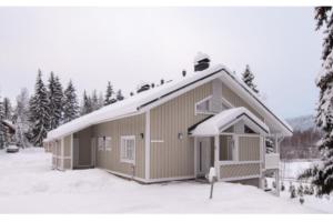 a house with a snow covered roof in the snow at Rivitalon lomahuoneisto Tahkolla in Tahkovuori