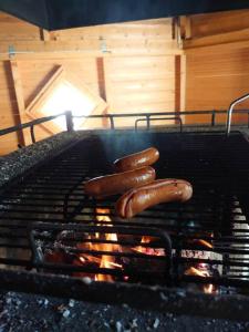 three hot dogs are cooking on a grill at Rivitalon lomahuoneisto Tahkolla in Tahkovuori