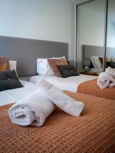a white towel laying on two beds in a room at 4 Putsborough - Luxury Apartment at Byron Woolacombe, only 4 minute walk to Woolacombe Beach! in Woolacombe
