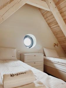 a bedroom with two beds and a round mirror at Sosnowe Domki in Warpuny