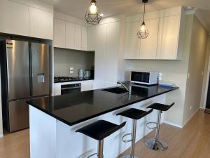 a kitchen with black counter tops and white cabinets at Delighted at Rotorua nearly Redwoods in Rotorua