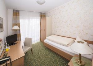 ein Hotelzimmer mit einem Bett und einem Schreibtisch mit einem Computer in der Unterkunft Land-gut-Hotel Rohdenburg in Lilienthal