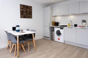 cocina con mesa, sillas y lavadora en 3 Putsborough - Luxury Apartment at Byron Woolacombe, only 4 minute walk to Woolacombe Beach!, en Woolacombe 26 fotos más