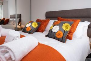 Una cama con almohadas naranjas y blancas. en 3 Putsborough - Luxury Apartment at Byron Woolacombe, only 4 minute walk to Woolacombe Beach!, en Woolacombe