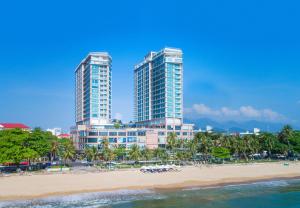 zwei hohe Gebäude an einem Strand neben dem Meer in der Unterkunft Diamond Bay Hotel in Nha Trang