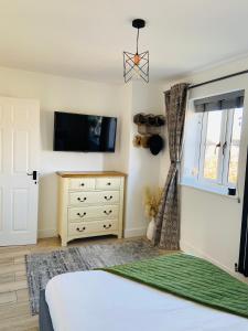 1 dormitorio con 1 cama, TV y vestidor en The Ely Retreat en Ely