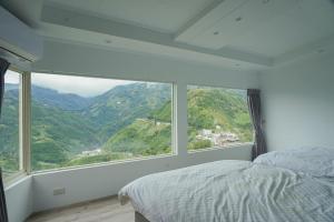a bedroom with a large window with a mountain view at Gegbyan in Ch'ia-la