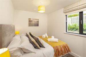 a bedroom with a large bed with a yellow blanket at 5 Putsborough - Luxury Apartment at Byron Woolacombe, only 4 minute walk to Woolacombe Beach! in Woolacombe
