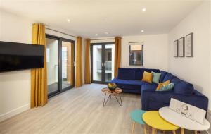 a living room with a blue couch and a tv at 5 Putsborough - Luxury Apartment at Byron Woolacombe, only 4 minute walk to Woolacombe Beach! in Woolacombe