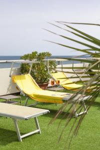 ein paar gelbe Stühle, ein Tisch und ein Boot in der Unterkunft Hotel Igea Spiaggia in Bellaria-Igea Marina