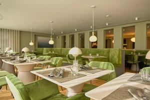 a restaurant with tables and green chairs at Hotel Atlantic Juist in Juist