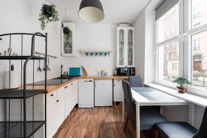 cocina con armarios blancos y suelo de madera en Piano Apartment w sercu Starego Miasta en Gdansk