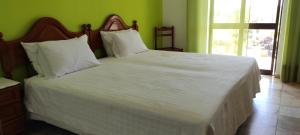 a bedroom with a large bed with white sheets and pillows at Vivenda Familia Pedro in Vila do Bispo