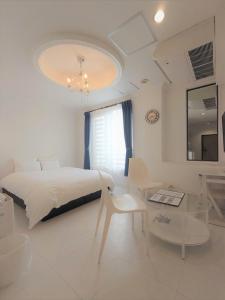 唐津市にあるシースタイルリゾートオーシャンの白いベッドルーム(大型ベッド1台、テーブル付)