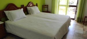 a bedroom with a large bed with white sheets and pillows at Vivenda Familia Pedro in Vila do Bispo