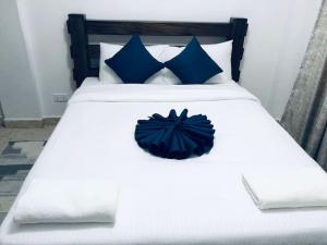 Elle comprend un grand lit blanc avec des oreillers bleus. dans l'établissement Arabel's Place 1 Bedroom California Plaza Nanyuki, à Nanyuki