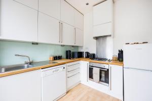 una cocina blanca con armarios blancos y fregadero en Stylish Apartment Opposite Westfields en Londres