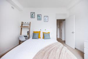 1 dormitorio con 1 cama blanca grande con almohadas azules en Stylish Apartment Opposite Westfields en Londres