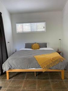 a bedroom with a bed with a yellow blanket on it at Innisfree, a secluded rainforest retreat in Tarzali