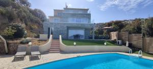 eine Villa mit einem Pool vor einem Haus in der Unterkunft F4 à Porticcio avec piscine et vue sur mer in Porticcio