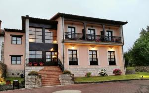 a large house with black windows and balconies at Hotel Rural El Texeu in Llanes