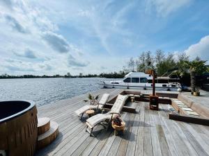un molo con sedie a sdraio e una barca sull'acqua di NEW - LITTLE IBIZA, on a lake near Amsterdam, with HOT TUB! a Vinkeveen