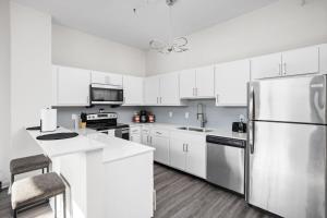 a kitchen with white cabinets and a stainless steel refrigerator at 2BR 2BA In The Block Apartment by CozySuites in Indianapolis