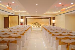 a banquet hall with rows of chairs and a stage at Hotel Tulips Grand in Hyderabad
